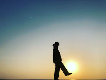 Silhouette man standing against clear sky during sunset