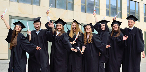 Cheerful friends wearing graduation gown