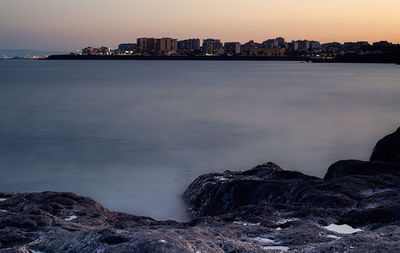 Sea by cityscape against sky