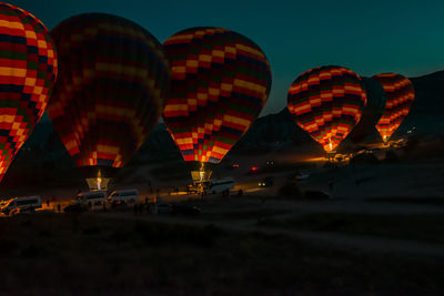 Illuminated hot air balloons against sky at night