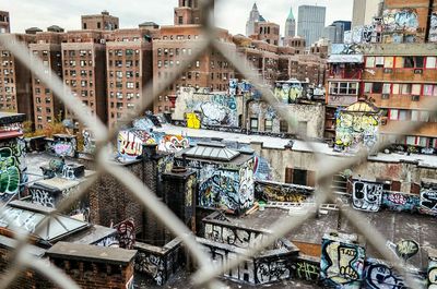 Graffiti on buildings seen through chainlink fence