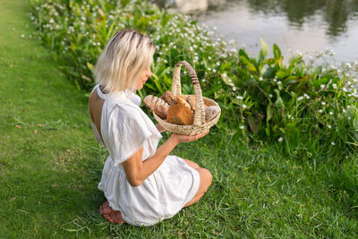 High angle view of woman with bread in basket on grass