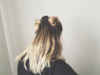 Rear view of woman standing against wall at home