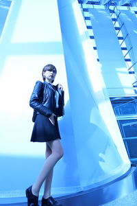 Low angle view of woman standing against blue wall