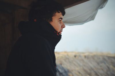 Side view of man looking out through window