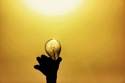 Low angle view of hand holding light bulb