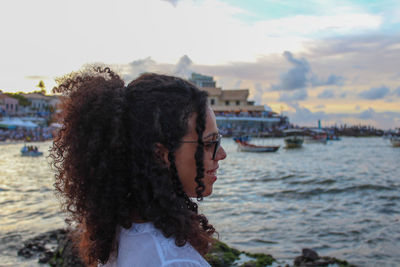 Side view of young woman looking at sea against sky