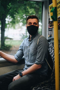Portrait of mid adult man wearing mask sitting in bus