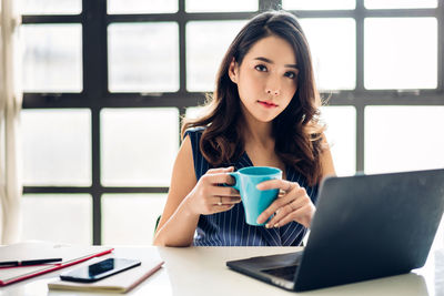 Young woman drinking coffee cup on table