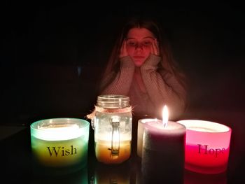 Woman with various candles glowing on table in darkroom