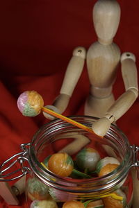 Close-up figurine with colorful lollipops in jar on red fabric