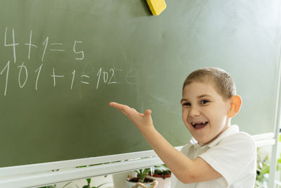 Side view of boy playing with text against wall