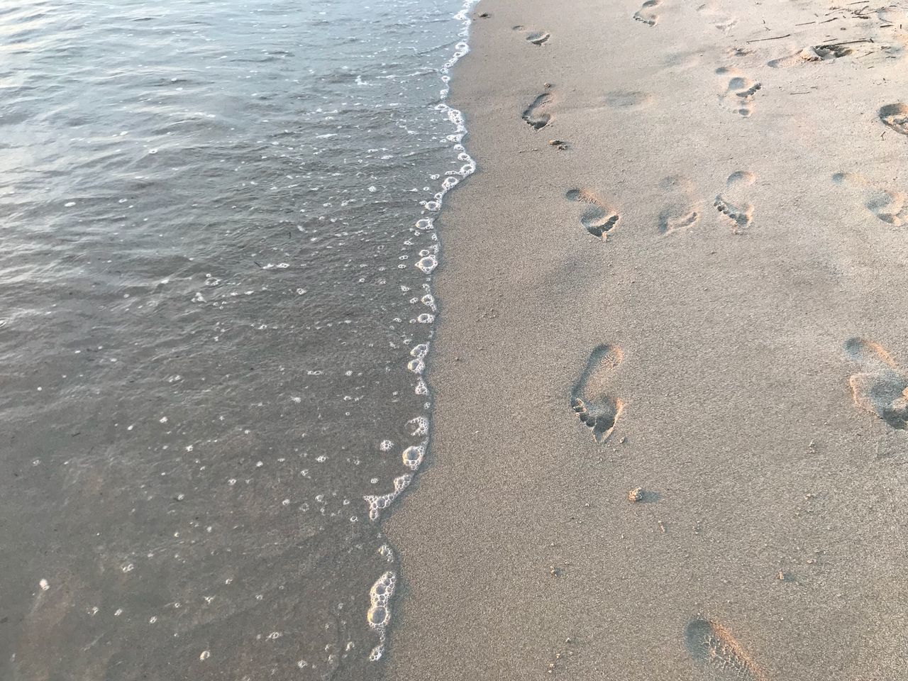 HIGH ANGLE VIEW OF FOOTPRINTS ON WET SAND AT BEACH