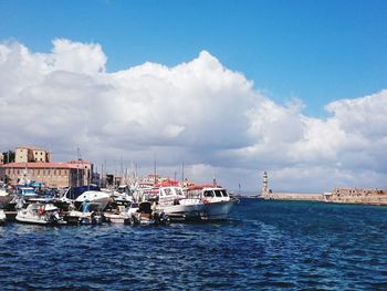 Sailboats moored on sea against cloudy sky