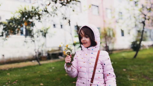 Girl holding flower standing on field