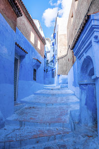 Narrow alley of blue town with staircase leading to residential structures on both side