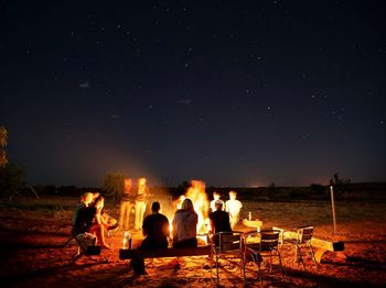 People enjoying bonfire against sky at night