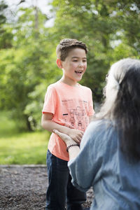 Cheerful boy holding hands with grandmother in back yard