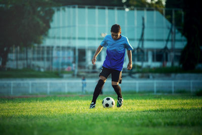 Rear view of man playing soccer ball on field