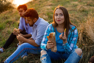 Portrait of smiling friends sitting on field