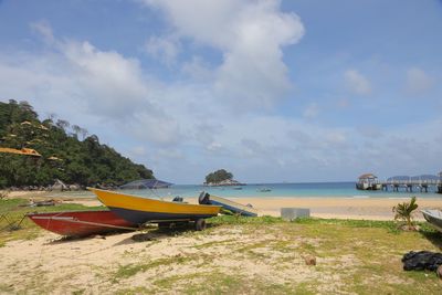 Boat moored on beach against sky