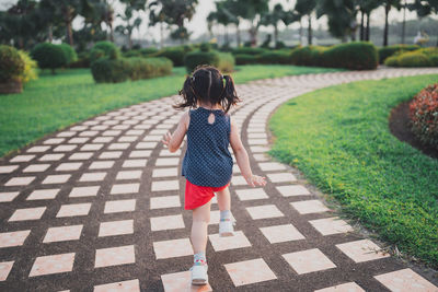 Rear view of girl walking on street at park