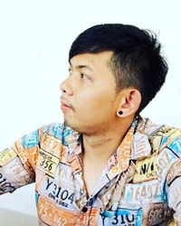 Portrait of young man looking away against white background