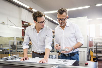 Two businessmen in factory discussing plan