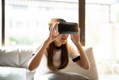 Curious woman with virtual reality headset at home