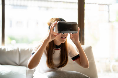 Woman using mobile phone while sitting on bed at home