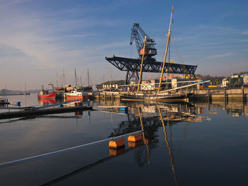 Crane at harbor against sky