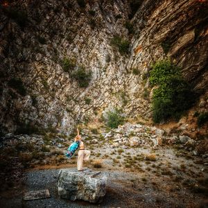 Full length of woman standing on rock against mountain