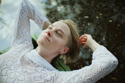 High angle view of thoughtful woman while lying outdoors