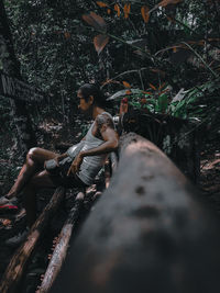 Woman sitting on tree trunk in forest