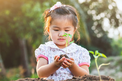 Cute girl planting sapling in garden