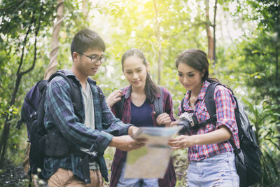 Friends using map in forest