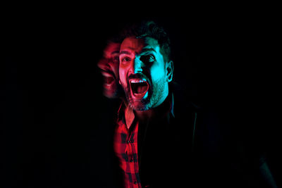 Portrait of young man against black background