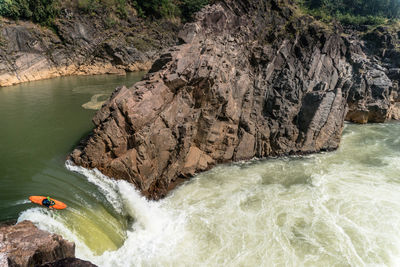 High angle view of man kayaking in sea against rock formation