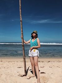Full length of young woman at beach against sky
