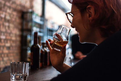 Midsection of woman drinking glass on table