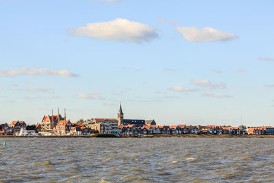 Buildings at waterfront against cloudy sky