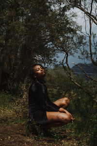 Young woman looking away while sitting on field
