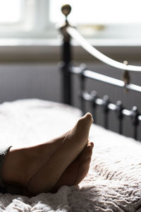 Low section of person relaxing on bed at home