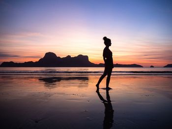 Silhouette man standing on beach against sky during sunset