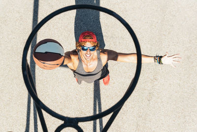 High angle view of man playing basketball seen through hoop