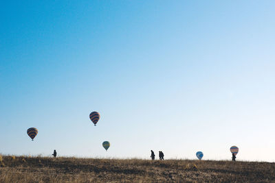 Hot air balloons on field against clear blue sky