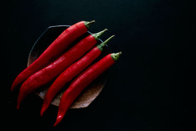 Close-up of red chili peppers on table against black background