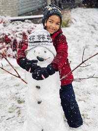 Portrait of smiling boy skiing on snow covered field