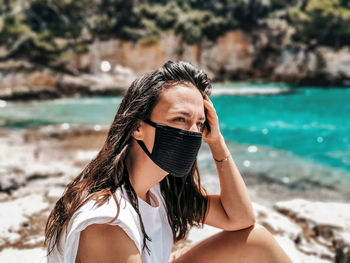 Young woman wearing black mask at beach. summer, tourism, virus, corona, covid-19.