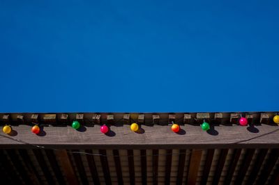 Low angle view of multi colored balloons against blue sky